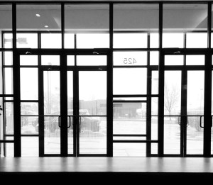 A black and white photo of the metal curtain wall of the door entrance at my job