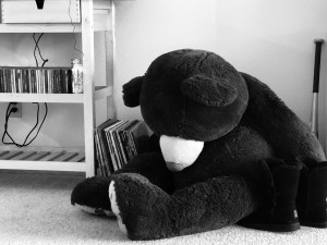 a black and white photo of my giant teddy bear seated, hunched over