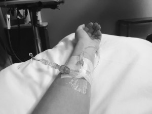 a black and white photo of my arm extended in a hospital bed with the infusion line hooked up to my arm