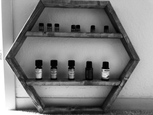 a black and white photo of my octagon wall hanging wooden shelf that holds an array of essential oils