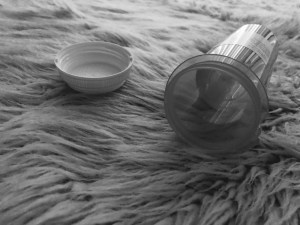 a black and white photo of an empty pill bottle on the floor
