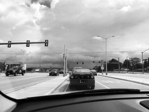a black and white photo of a threatening stormy sky above the traffic lights ahead