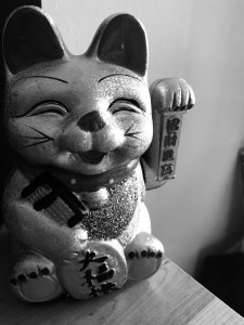 a black and white photo of a golden chinese cat figurine that stands for good luck and financial prosperity