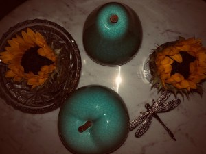 a faded dark photo looking down at some dying sunflowers surrounded by my blue ceramic apple and pear 