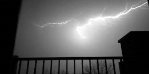 a black and white nightime capture of a bolt of lightning