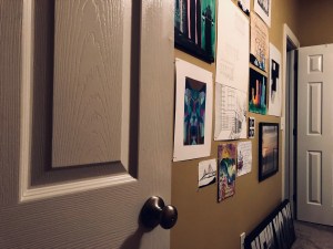 a color photo looking through my door at a wall lined with vibrant artwork I've made over the years 