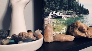 a color photo of the edge of bookshelf, a jewelry hand container is full of various crystals and larger gem specimens line the edge of a photography of northern wisconsin 
