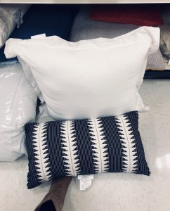 a pile of pillows, white and black and white striped in an aisle at a store