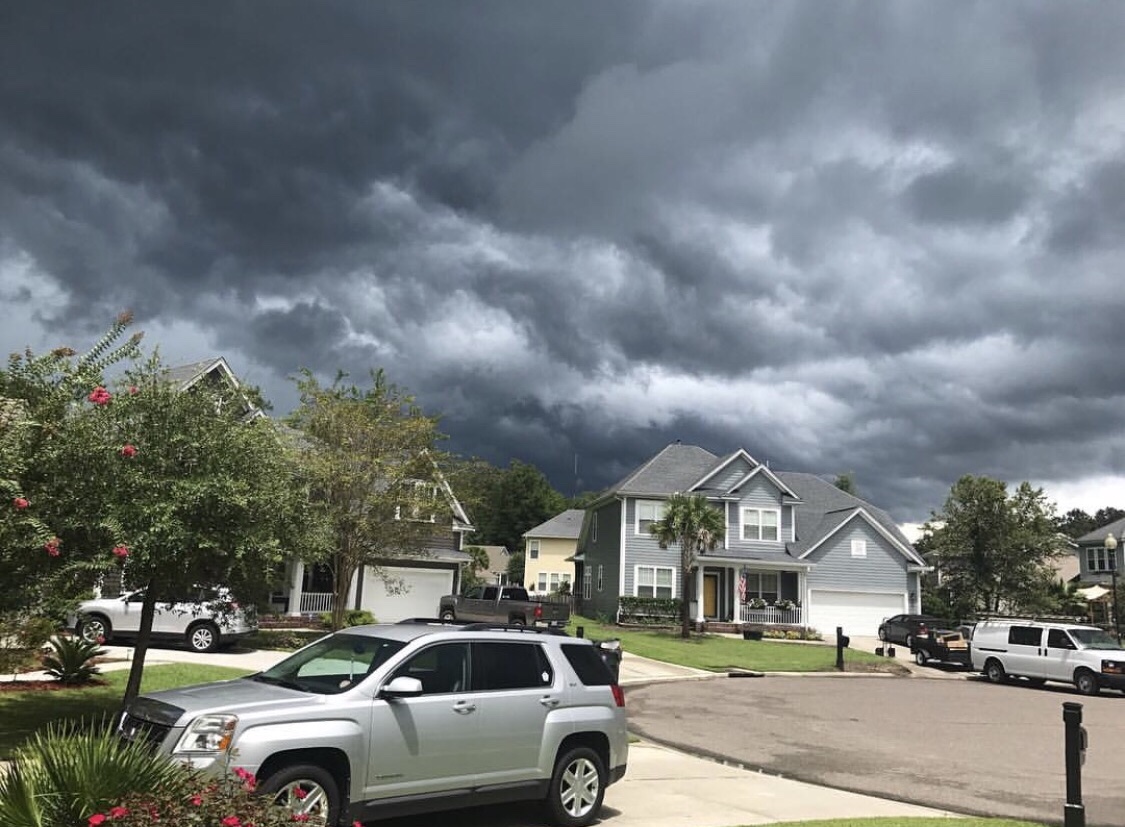 a stormy view of the houses around me, the sky dark shades of black and grey the sun still shining down