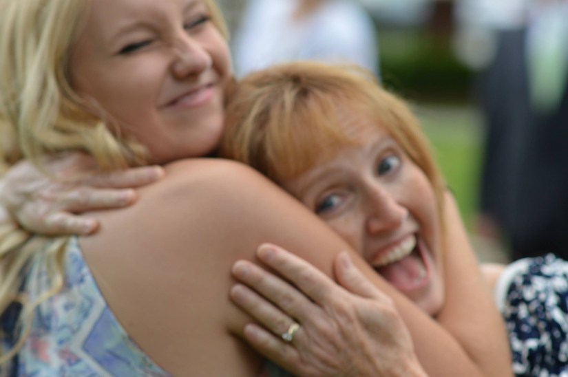 a slightly blurry photo of me hugging my mom tightly around her neck at a wedding