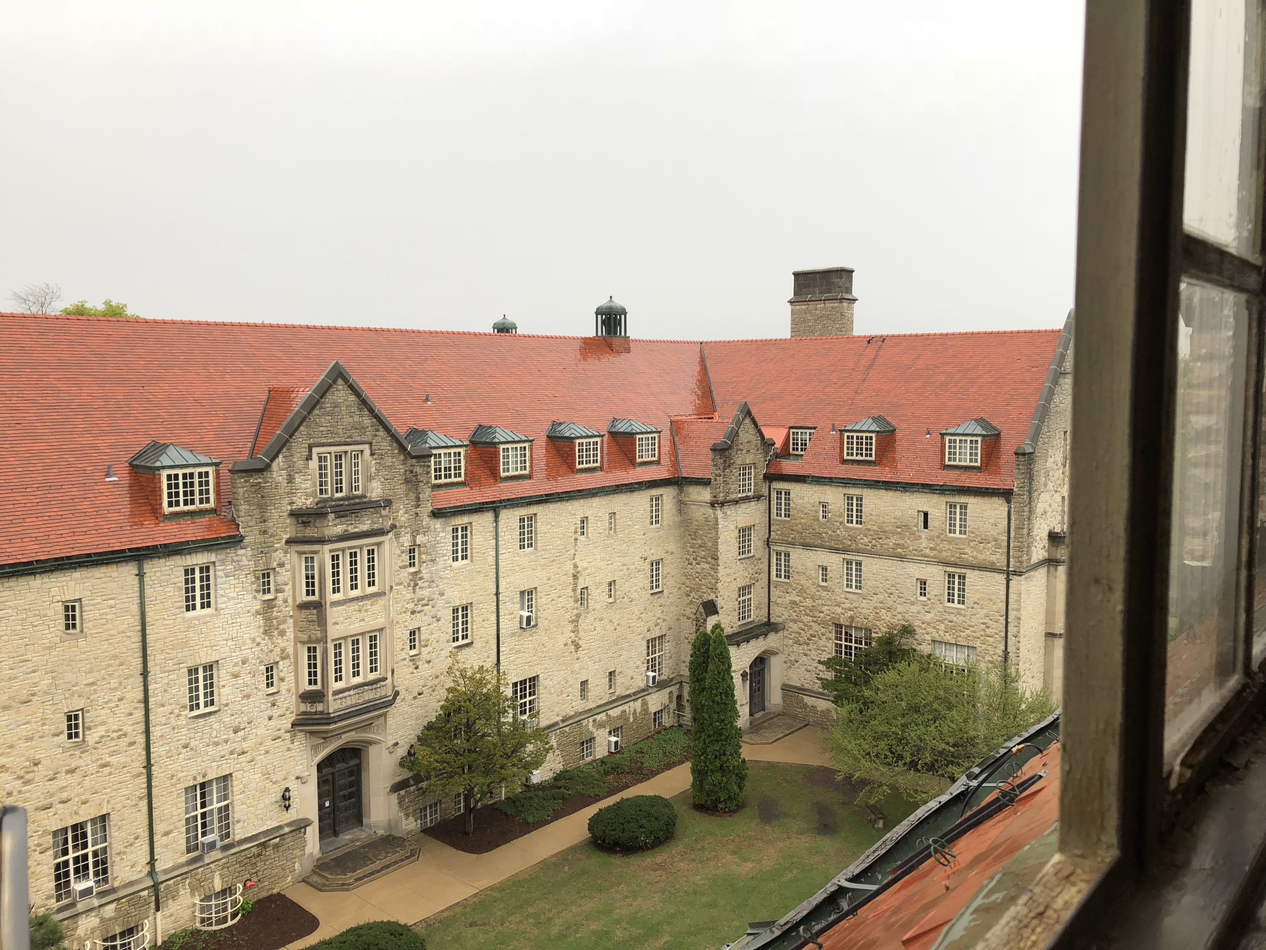 one of the large stone campus buildings at Mount Mary Univeristy with four stories and red tiled roof in the rain