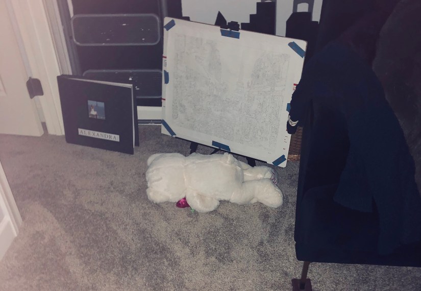 a dimly lit room with a small white teddy bear turned face down on the carpet laying lifeless