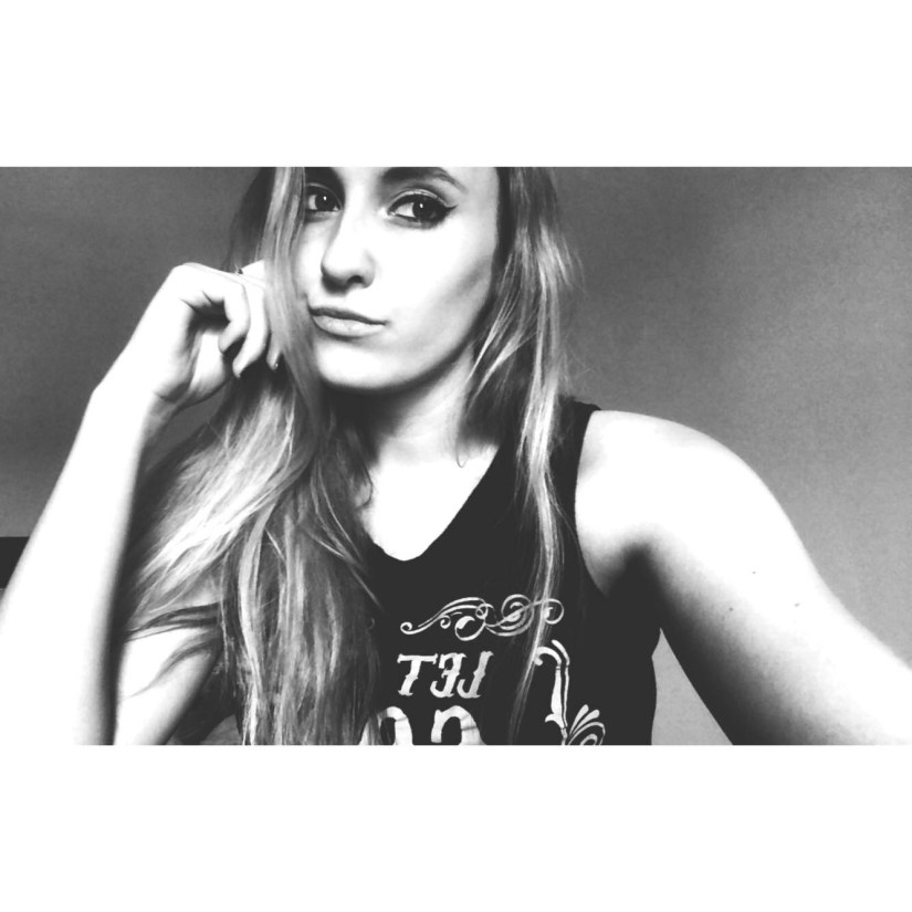 a black and white selfie, i'm wearing a black cut off sleeve shirt my hair straight and draped over to one side and my hand positioned near my face