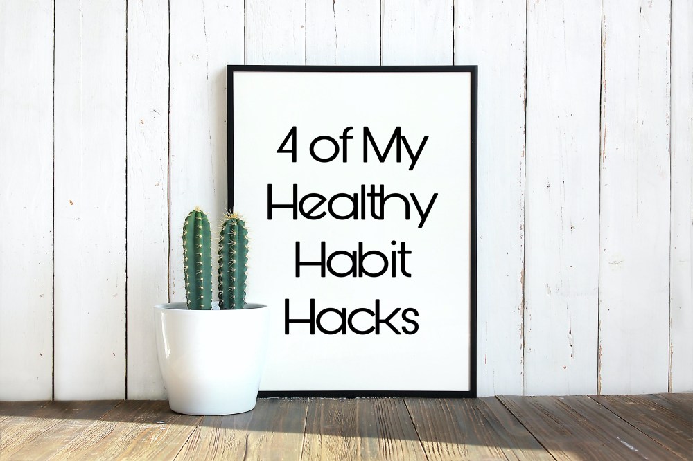 White paneled wall with a picture in black trim with text "4 of my healthy habit hacks" and a small potted cactus to the left of the picture.