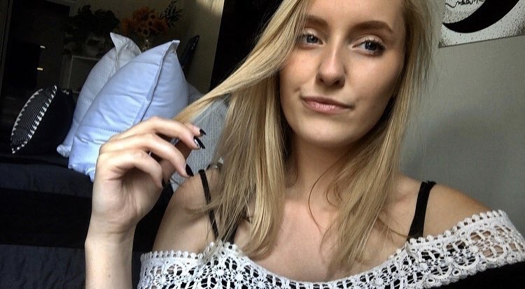 Blonde White woman pulling her hair aside with her hand.