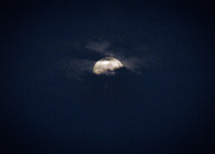 Full moon rising through thick clouds