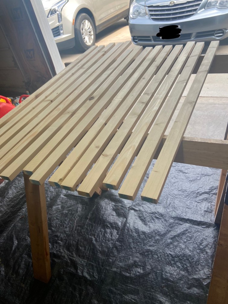 A dozen 1 x 2 boards have been laid across two stands in preparation to be stained