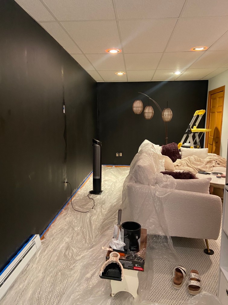 The living room still a mess, the walls now completely painted black and still drying.